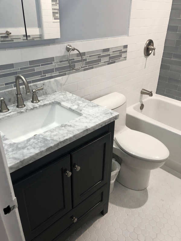 Bathroom with a grey vanity, marble countertop and new fixtures