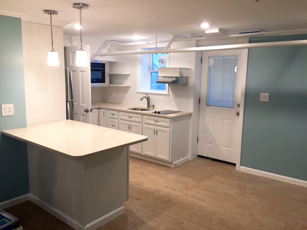 Renovated kitchen with a white island, pendant lights and white cabinetry
